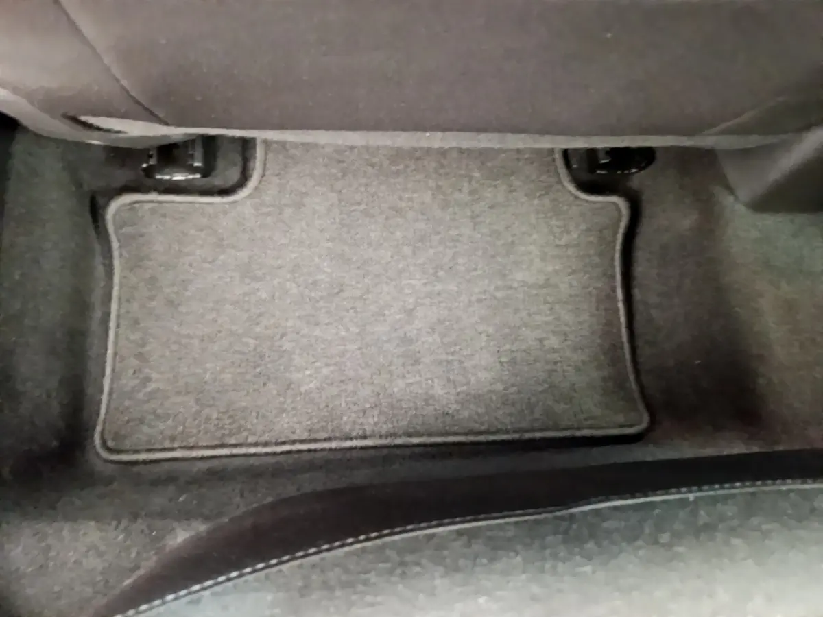 Tapis de sol gris foncé au pied du siège arrière d'une Renault Clio Business blanche vue de l'intérieur