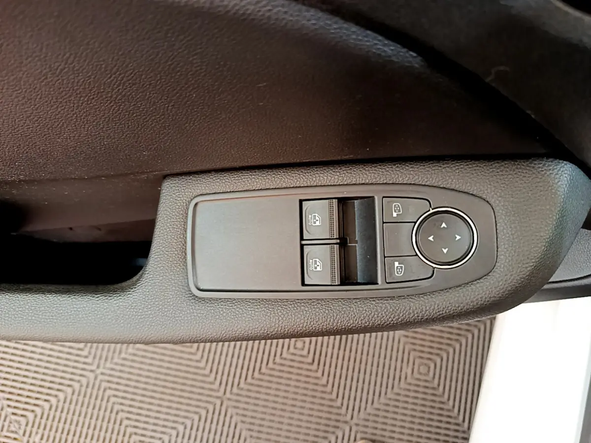 Gros plan sur les commandes de lève-vitres et réglage des rétroviseurs côté conducteur d'une Renault Clio blanche 2021