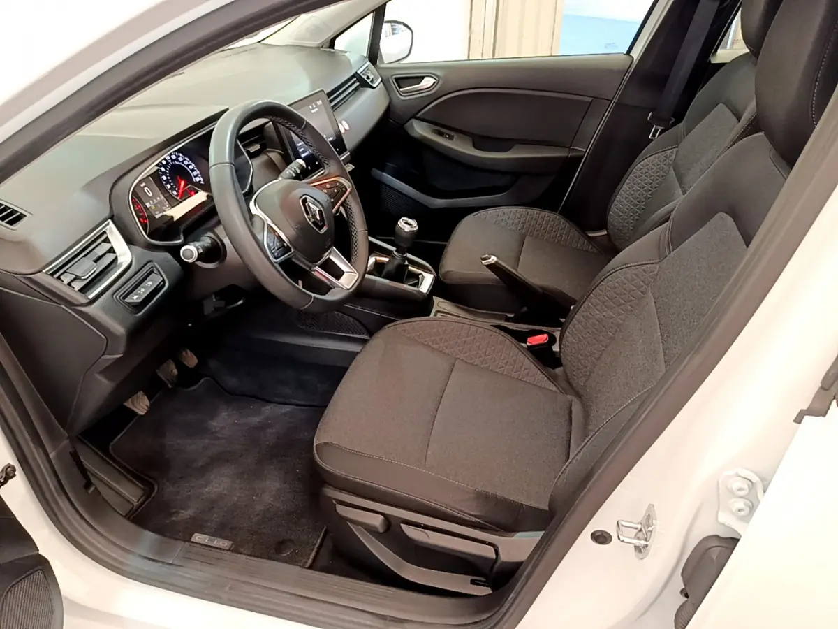 Intérieur côté conducteur d'une Renault Clio Business blanche 2021, volant cuir et sièges tissu gris foncé.