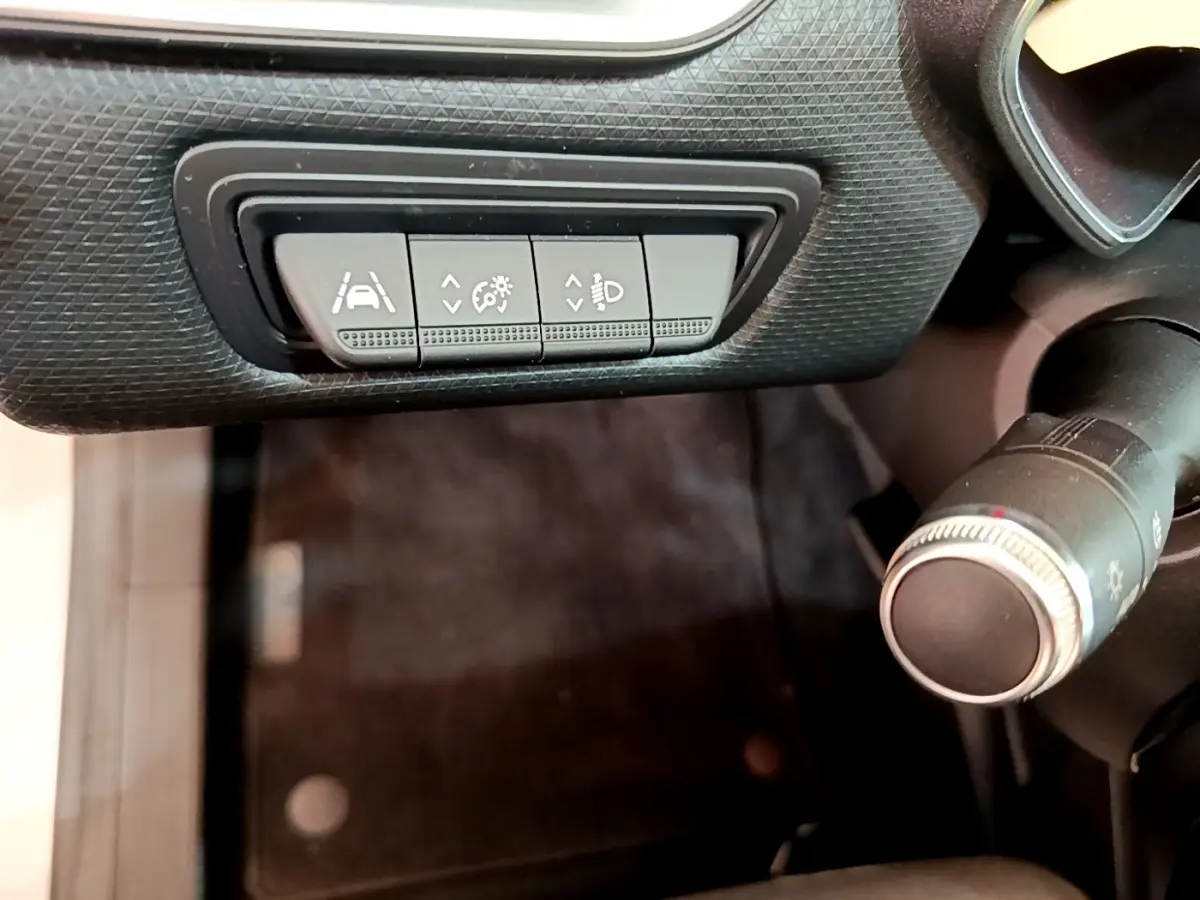 Gros plan sur les commandes d'assistance à la conduite et réglage des phares dans l'habitacle d'une Renault Clio blanche 2021.
