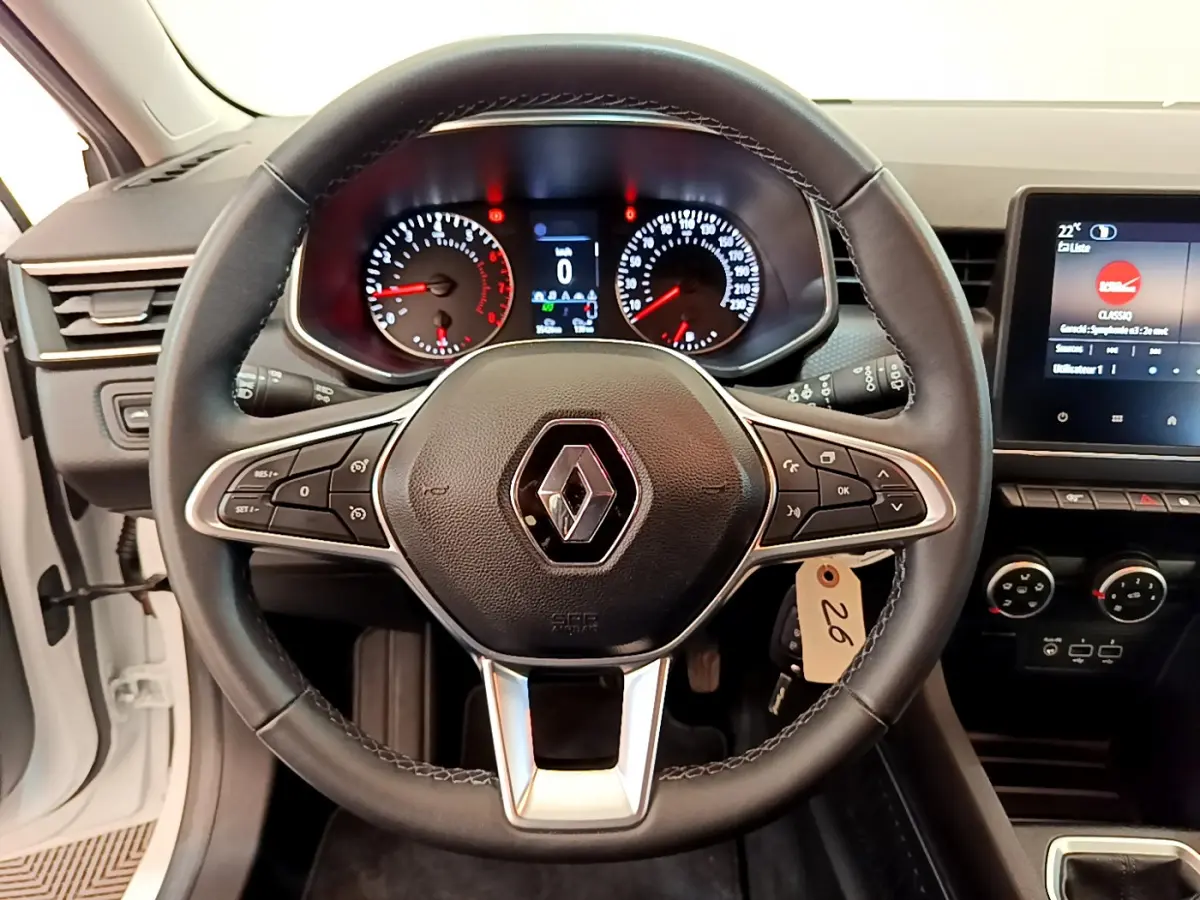 Vue centrée sur le volant cuir noir et le tableau de bord numérique de la Renault Clio Business blanche 2021.