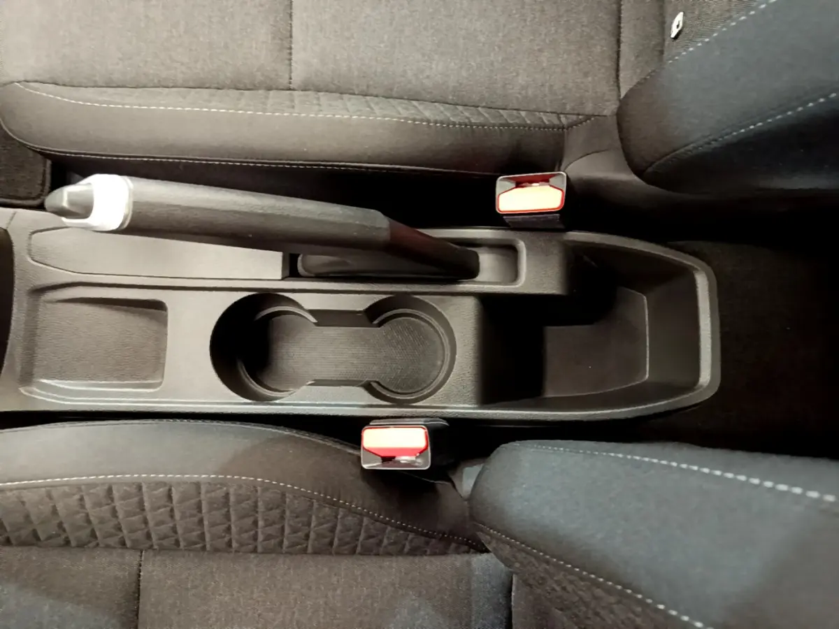 Vue plongeante sur la console centrale noire de la Renault Clio Business 2021 avec frein à main manuel et porte-gobelets.