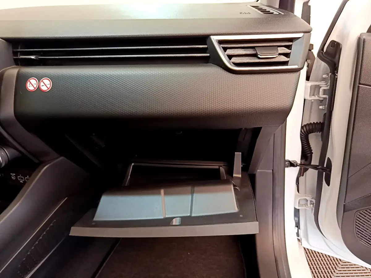 Gros plan sur la boîte à gants ouverte côté passager d'une Renault Clio Business blanche, intérieur noir texturé.