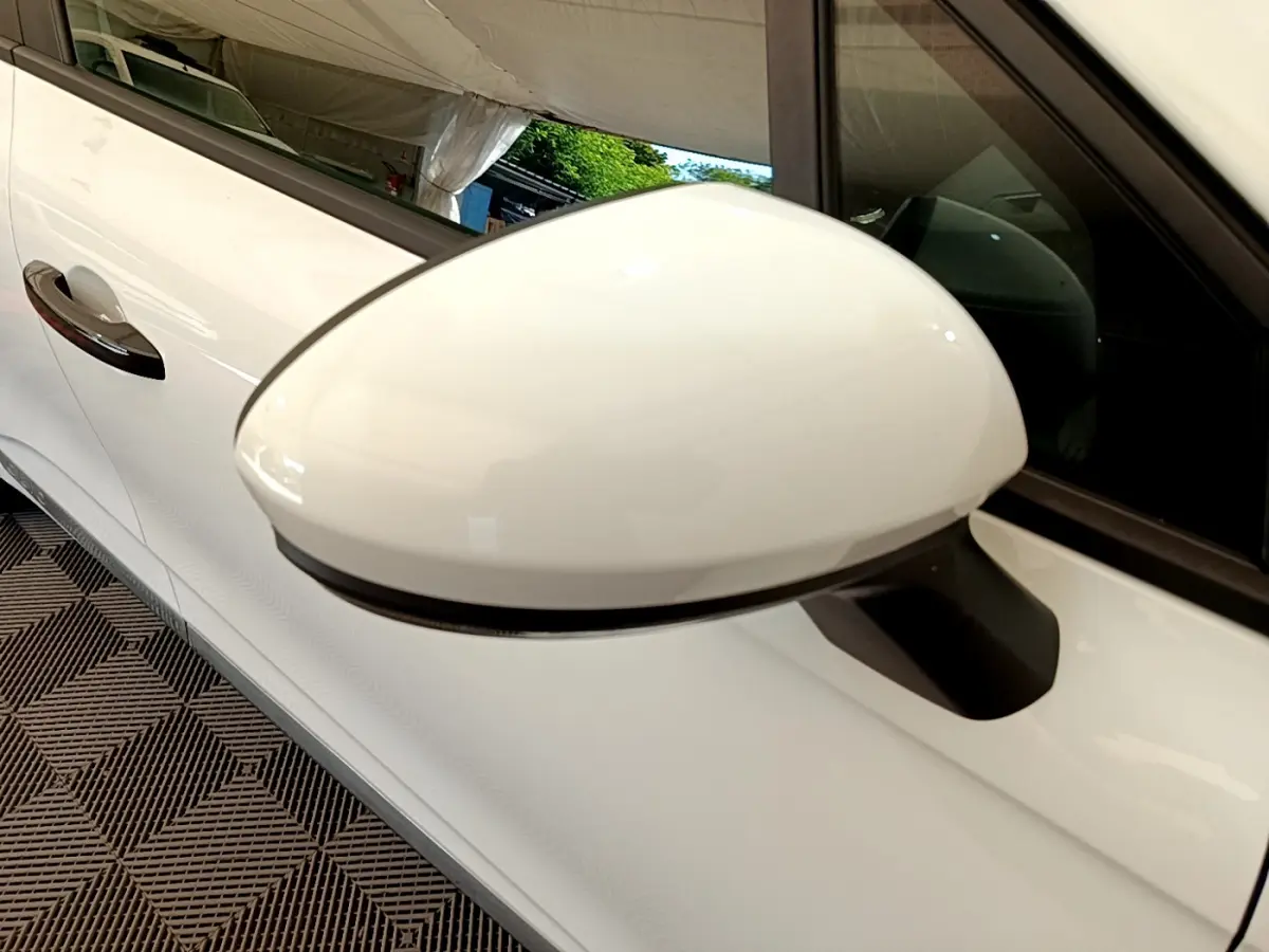 Rétroviseur côté gauche blanc en gros plan sur Renault Clio Business 2021, avec porte et poignée visibles.