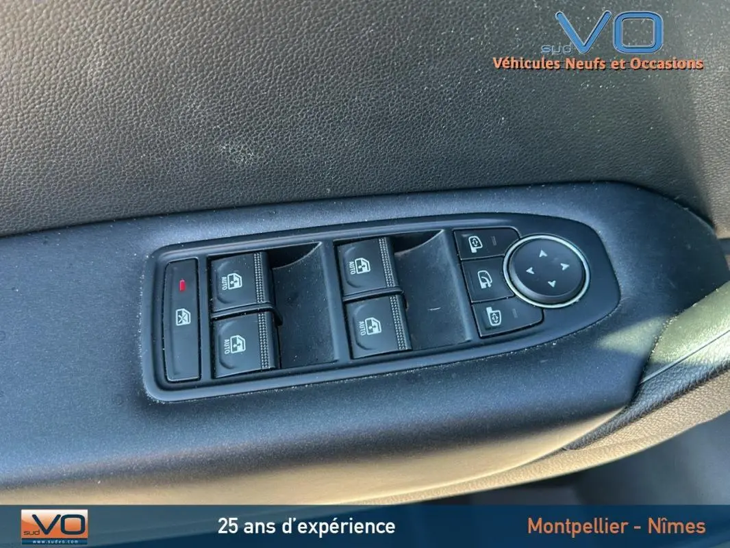 Gros plan sur les commandes des vitres électriques et rétroviseurs sur la porte côté conducteur d'un Renault Captur gris 2021.