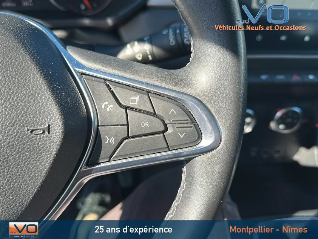 Gros plan sur les commandes au volant du Renault Captur gris, version TCe 90 Business, avec tableau de bord en arrière-plan.