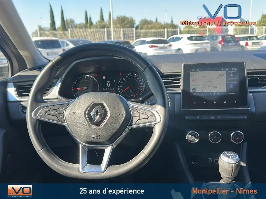 Vue intérieure du tableau de bord et volant du Renault Captur gris TCe 90 21 Business avec boîte manuelle et écran tactile central.