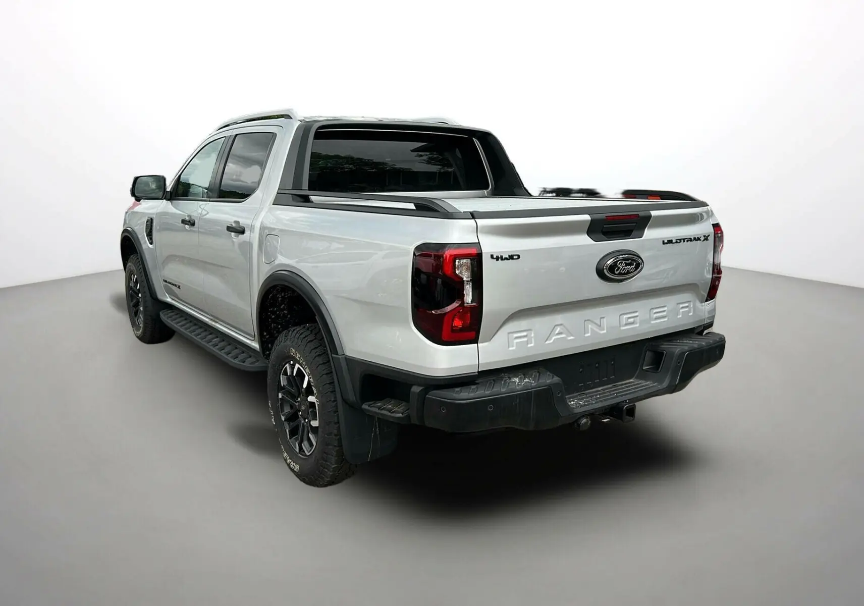 Vue 3/4 arrière droite du Ford Ranger 2025 gris iconic avec arceau sport, barres de toit et ridelles noires.