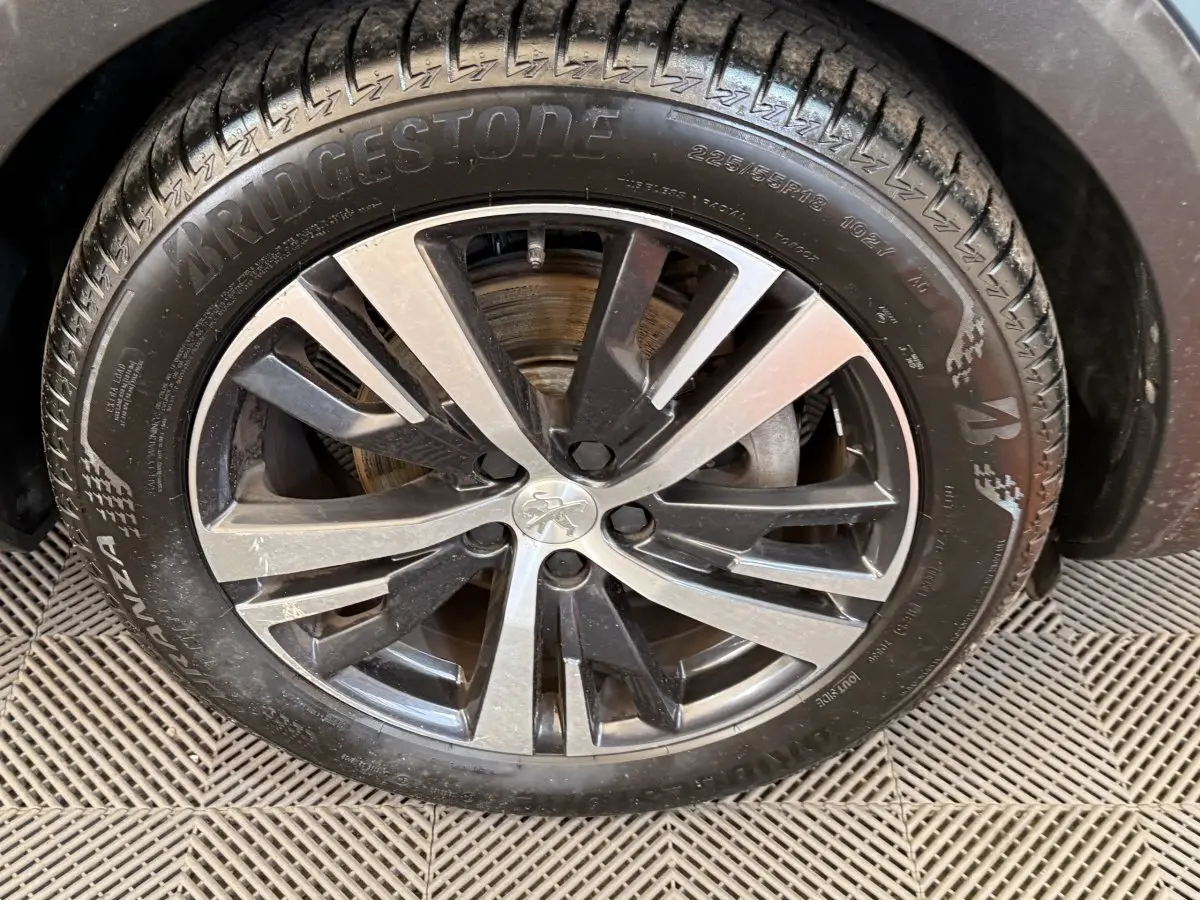 Gros plan sur la jante alliage bicolore et pneu Bridgestone du côté avant droit du Peugeot 5008 bleu.