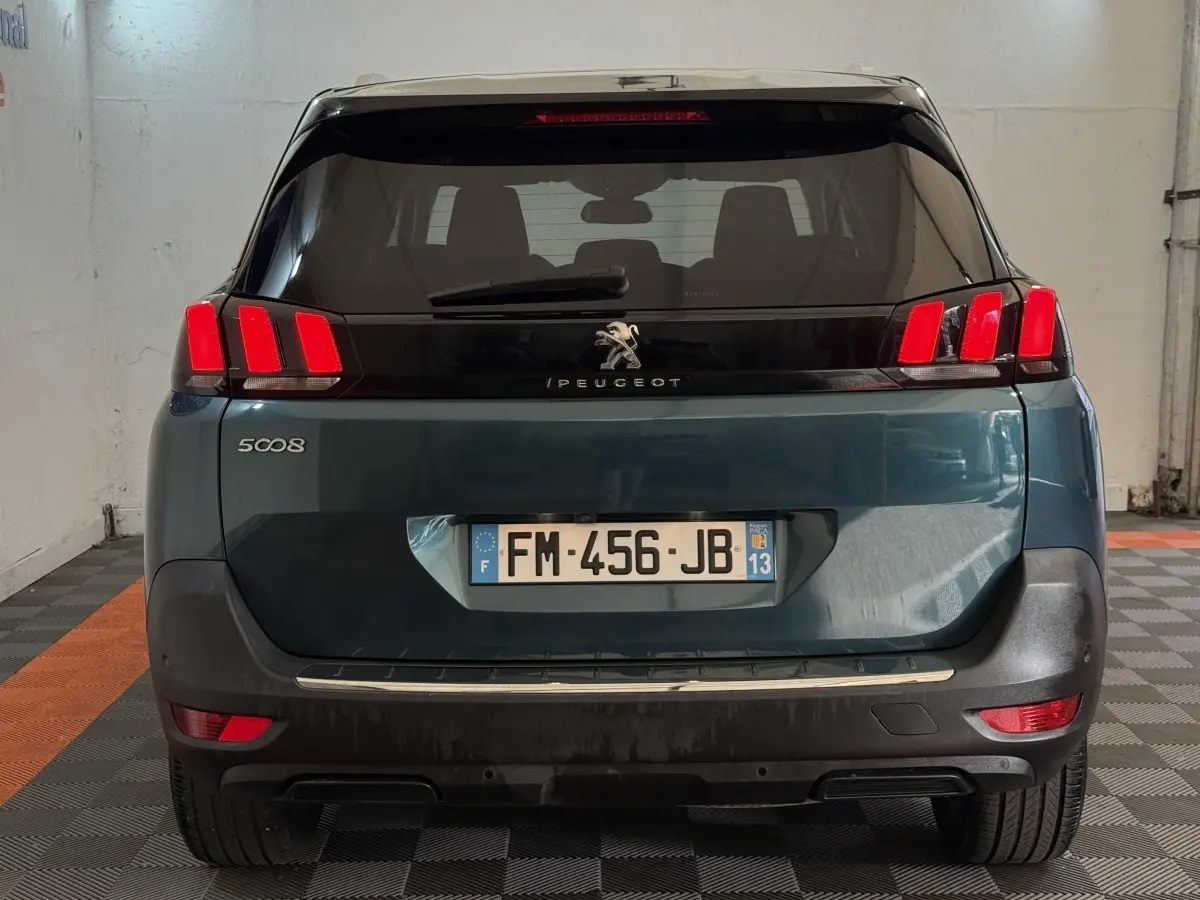 Vue arrière d’un Peugeot 5008 bleu avec feux arrière à trois griffes rouges et plaque d’immatriculation française.