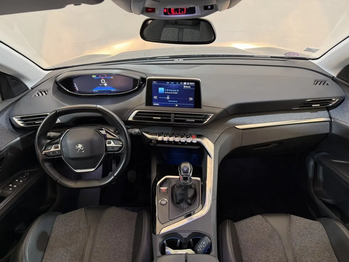 Vue intérieure avant du tableau de bord noir et gris du Peugeot 5008 Puretech 130 avec volant cuir multifonctions et écran tactile central.