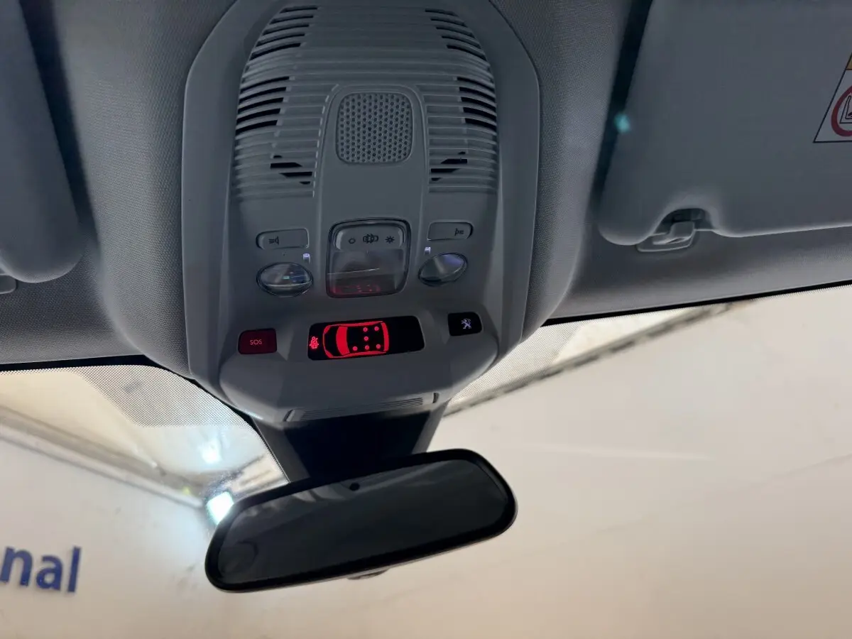 Vue intérieure en plongée du plafonnier gris avec commandes lumineuses et rétroviseur intérieur d’un Peugeot 5008 bleu.