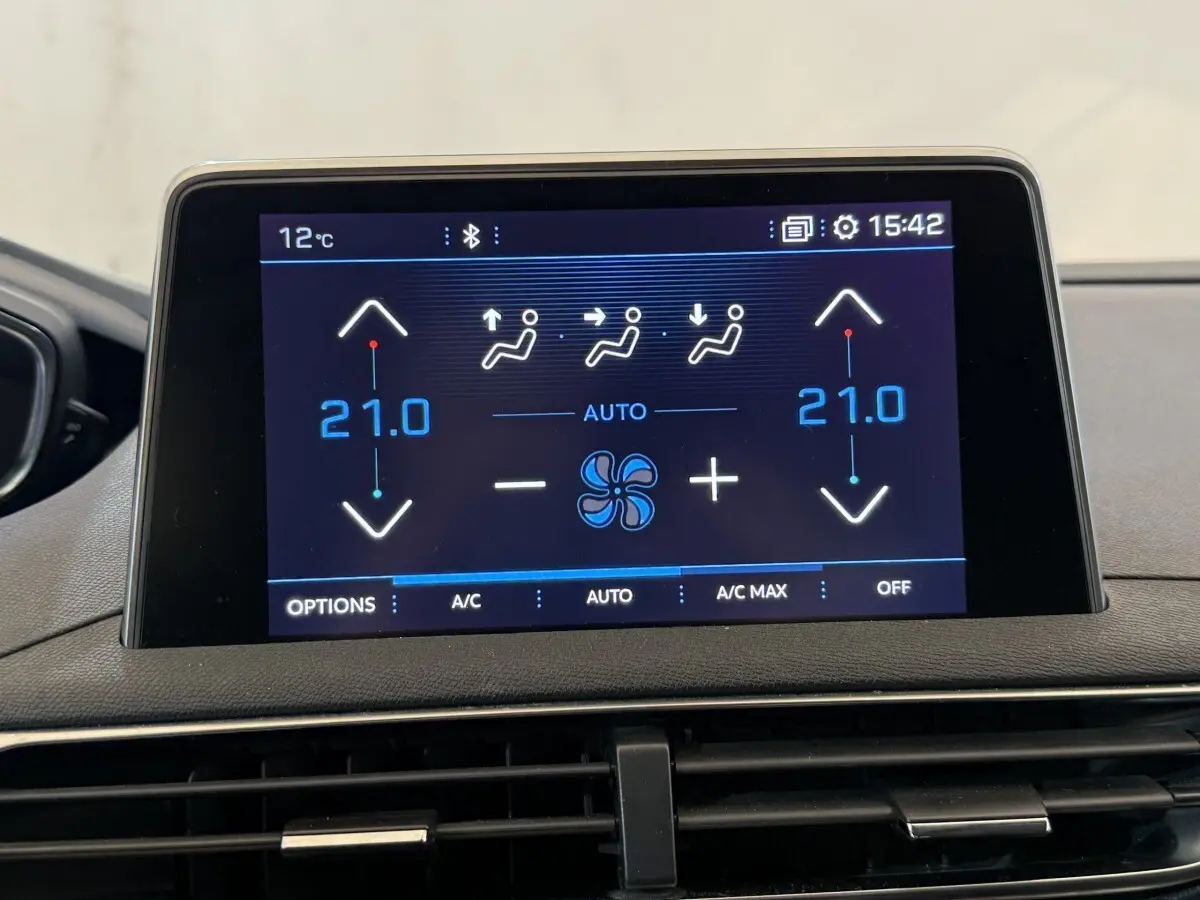 Écran tactile central du tableau de bord du Peugeot 5008 bleu, affichant la climatisation à 21°C en mode automatique.