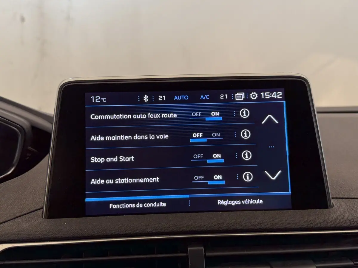 Écran tactile central du Peugeot 5008 bleu, affichant les réglages d’aides à la conduite, vue intérieure frontale.