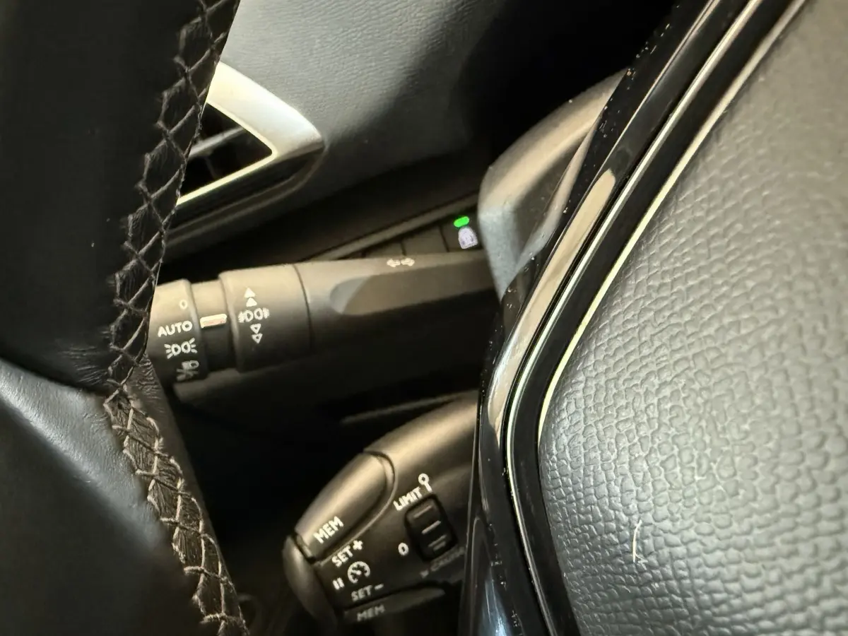 Gros plan sur le volant cuir noir et les commandes de régulateur de vitesse du Peugeot 5008 bleu, version Allure.