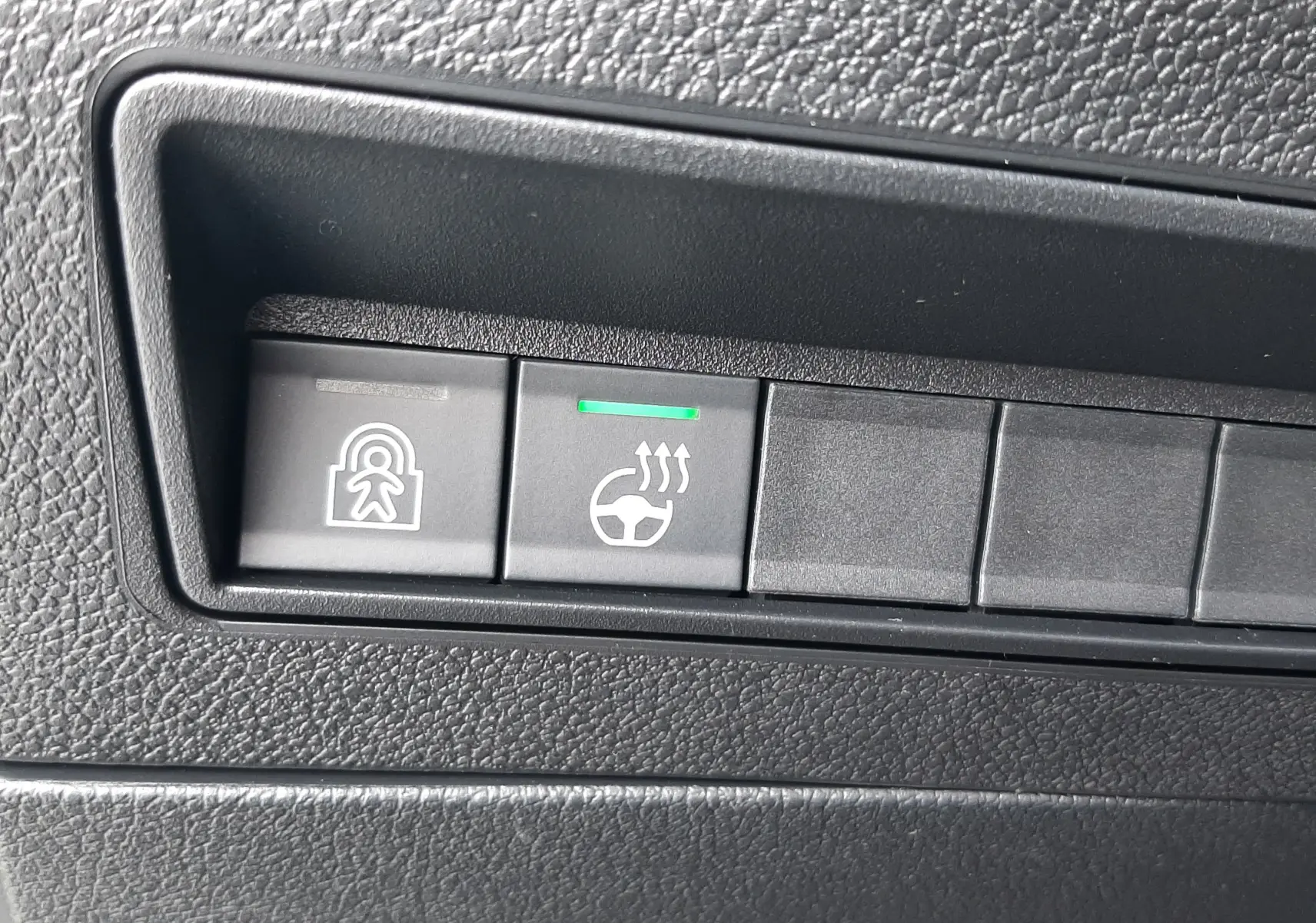 Gros plan sur les boutons de commande du Peugeot Rifter 2026, avec témoin vert sur le chauffage du volant.
