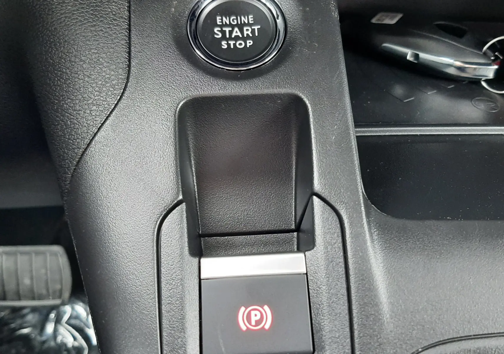 Gros plan sur la console centrale du Peugeot Rifter bleu Kiama, montrant le bouton start/stop et le frein à main électronique.