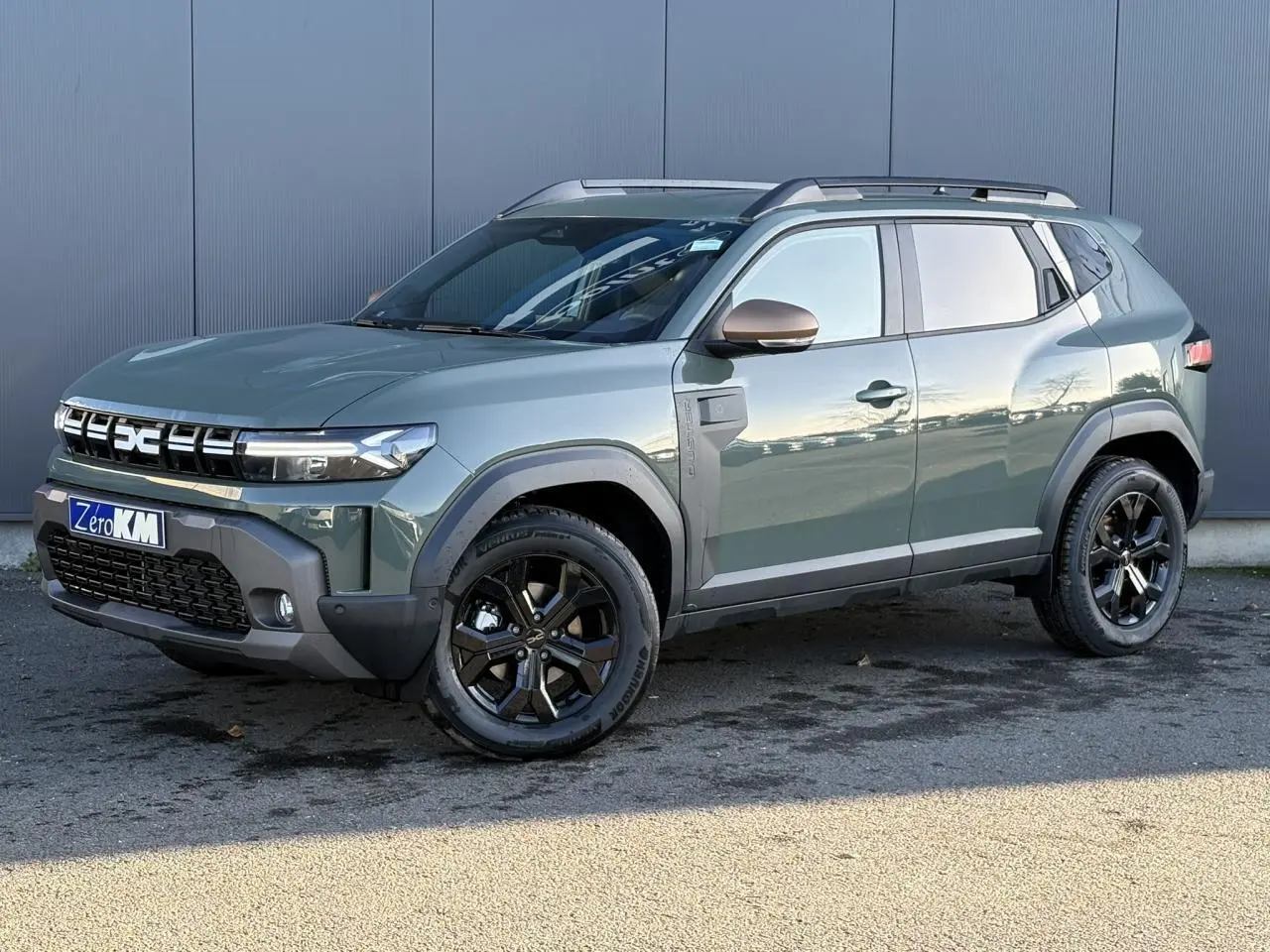 Dacia Duster ECO-G 120 Auto Extrême kaki lichen en 3/4 avant droit avec jantes noires et barres de toit.