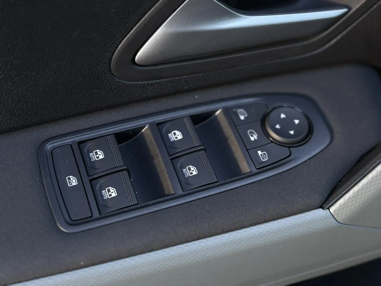 Gros plan sur les commandes de lève-vitres et rétroviseurs sur la porte côté conducteur du Dacia Duster kaki.