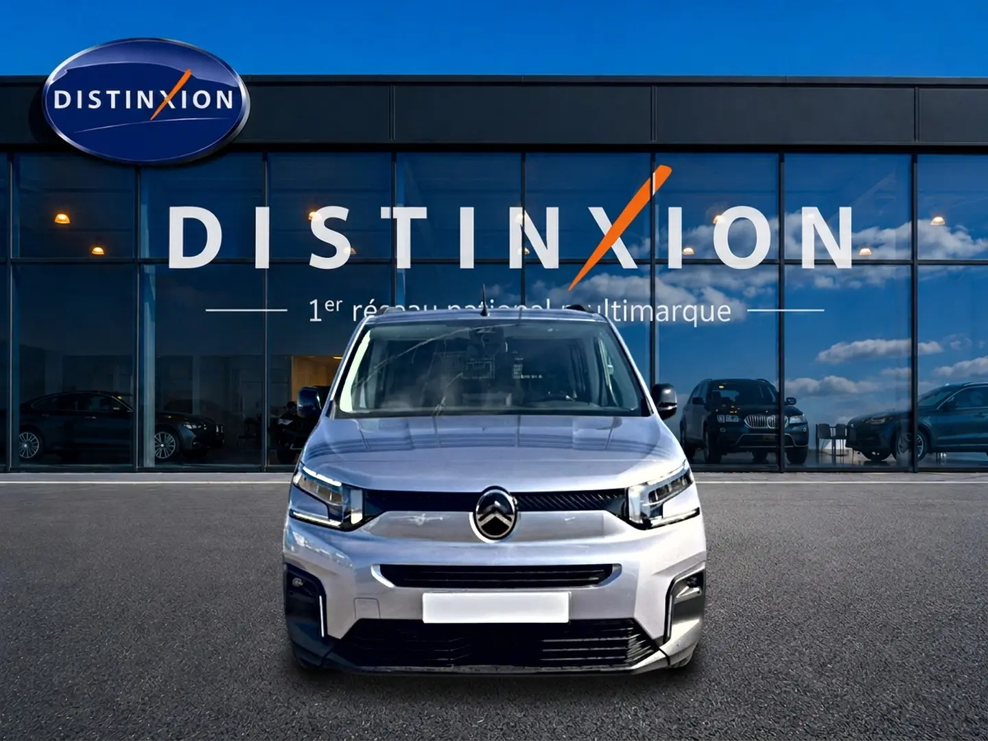 Vue avant d'un Citroën Berlingo 2026 gris acier, avec calandre noire et phares LED devant un showroom Distinxion.
