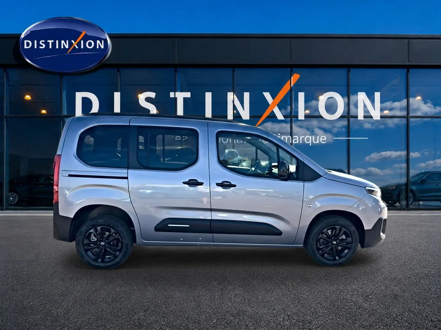 Vue latérale gauche d'un Citroën Berlingo Steel Grey 2026 avec jantes noires et barres de toit visibles.