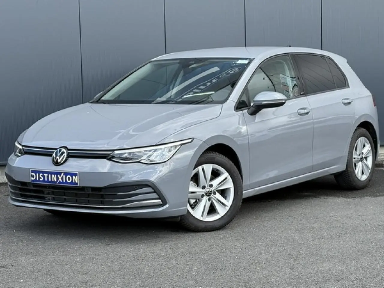 Volkswagen Golf VIII 1.5 TSI gris lunaire vue 3/4 avant droit avec jantes alliage 16 pouces et vitres teintées.