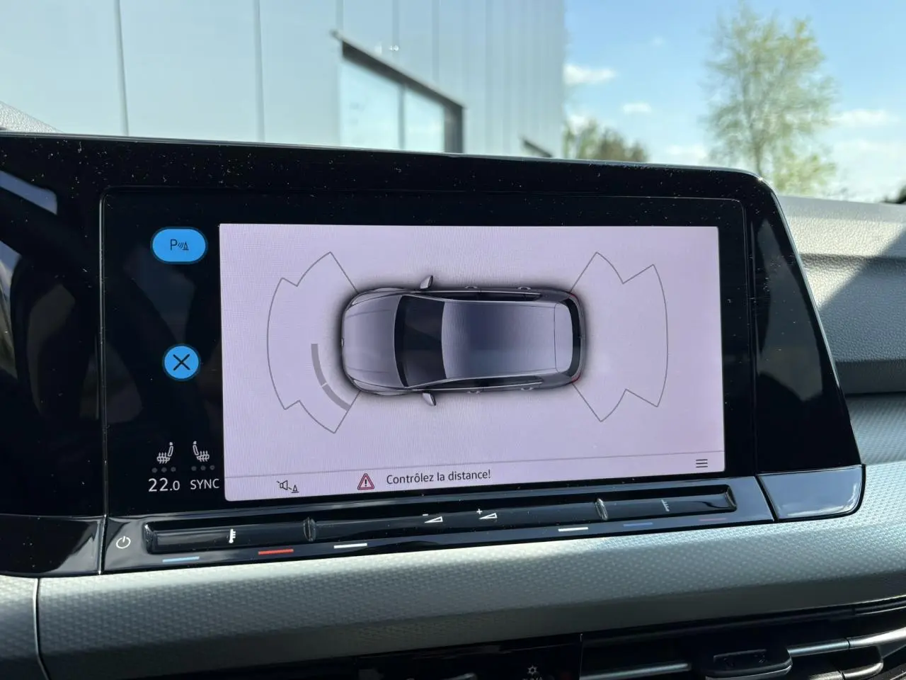 Écran tactile intérieur affichant la vue aérienne de la Volkswagen Golf VIII gris lunaire avec capteurs de stationnement actifs.