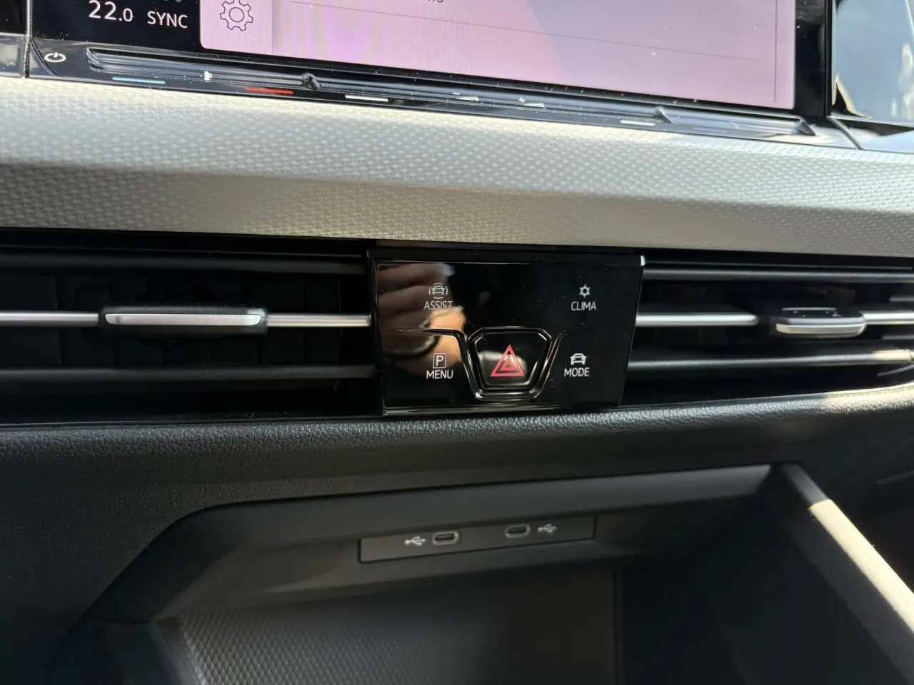 Détail du tableau de bord de la Volkswagen Golf VIII gris lunaire, avec commandes centrales et prises USB visibles.