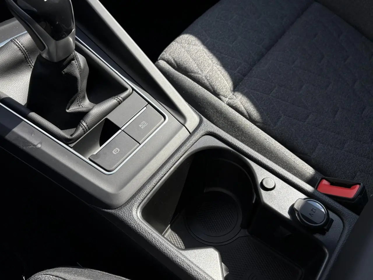 Gros plan sur la console centrale noire avec levier de vitesse manuel et porte-gobelet du Volkswagen Golf VIII Gris Lunaire.