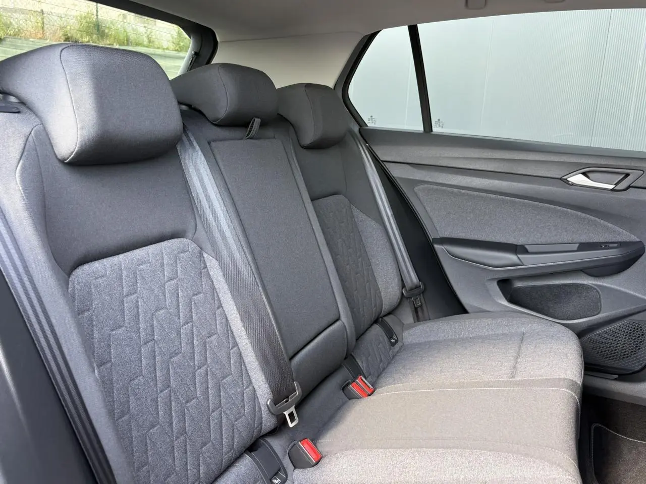 Vue latérale droite de la banquette arrière grise de la Volkswagen Golf VIII 1.5 TSI 2024 avec ceintures et appuie-têtes.