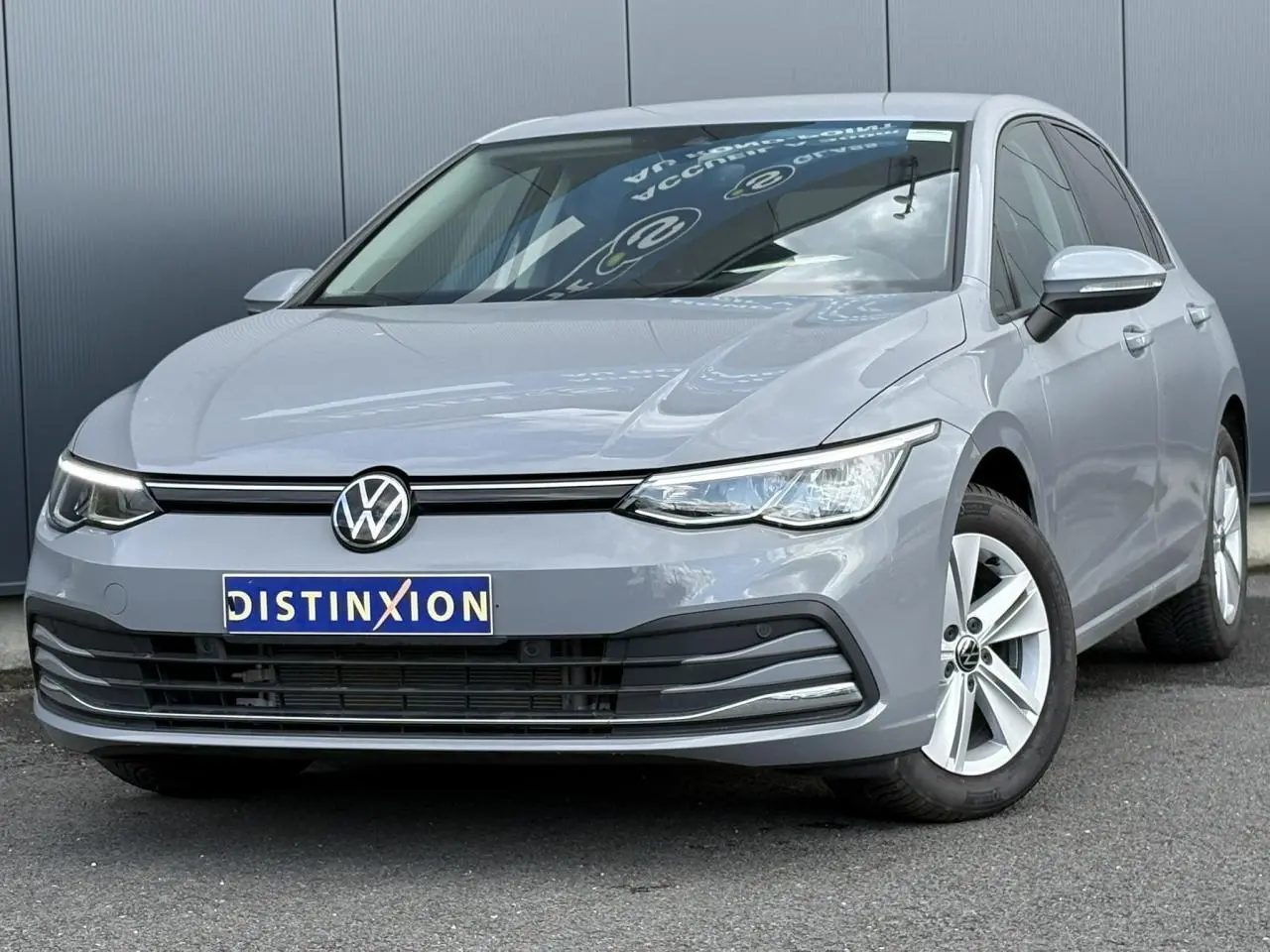 Volkswagen Golf VIII 1.5 TSI gris lunaire vue 3/4 avant droit avec jantes alliage 16 pouces et calandre noire.