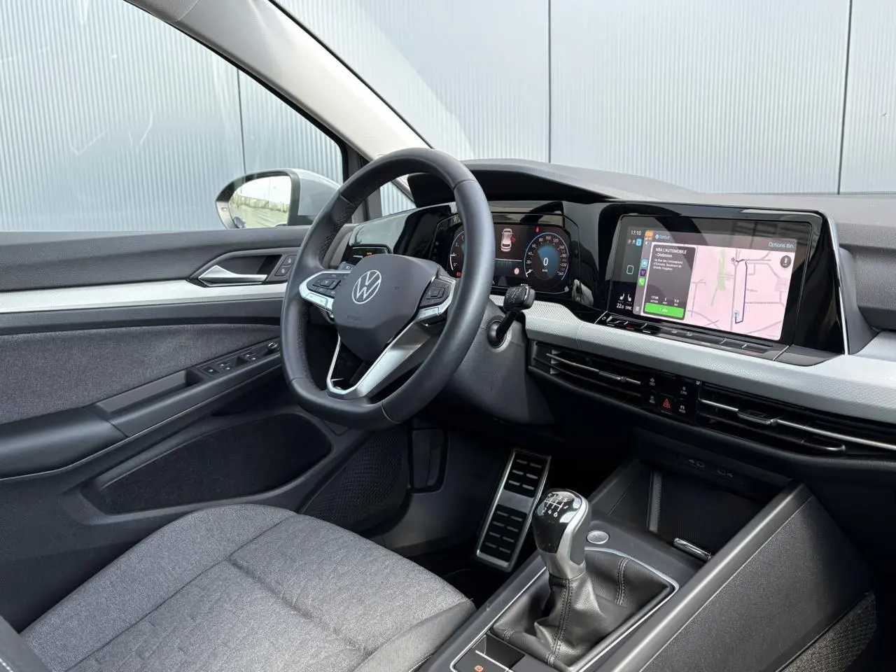 Intérieur de la Volkswagen Golf VIII essence 2024, vue côté conducteur, volant cuir multifonction et écran tactile navigation.