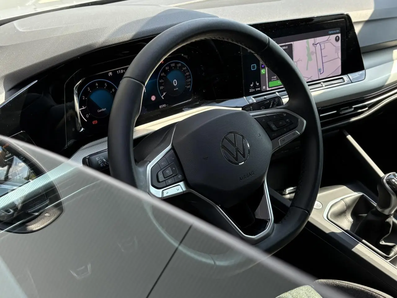 Vue rapprochée de l'intérieur de la Volkswagen Golf VIII 1.5 TSI 2024, volant cuir multifonction et écran tactile.