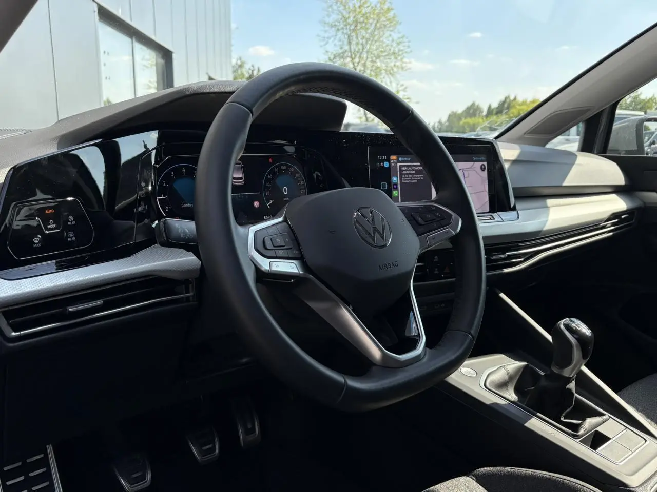 Vue intérieure de la Volkswagen Golf VIII 1.5 TSI 2024, volant cuir multifonction et levier de vitesse manuel visibles.