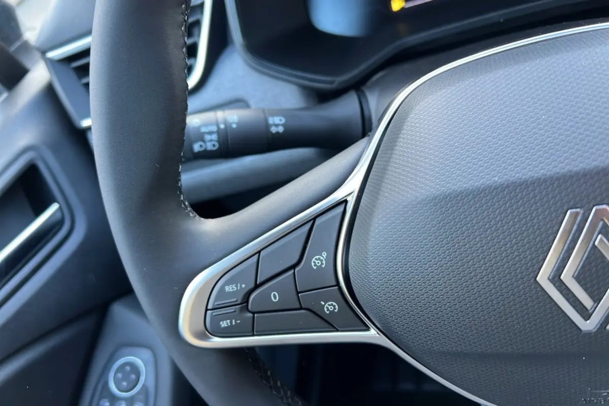 Gros plan sur le volant noir de la Renault Clio 2025, avec commandes de régulateur de vitesse intégrées.