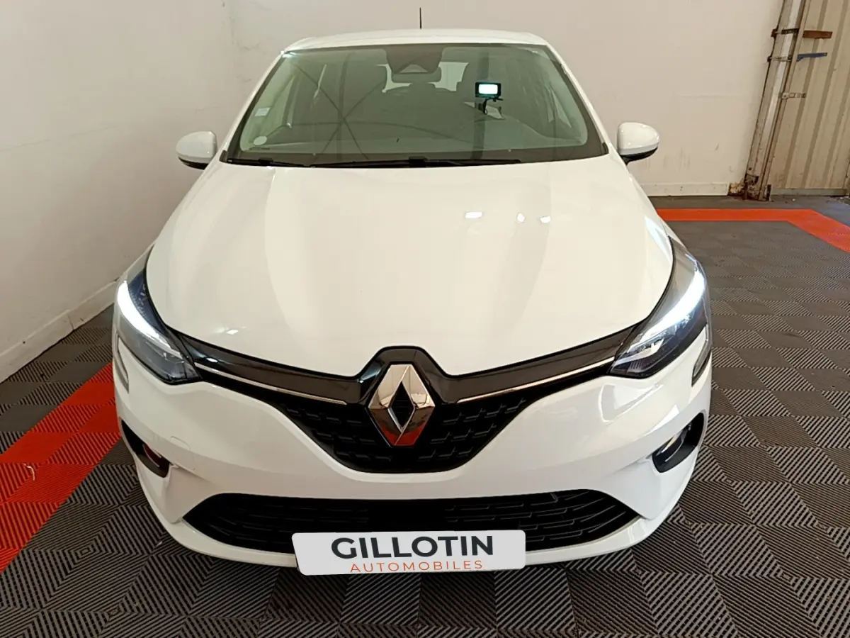 Vue avant d'une Renault Clio Business blanche avec phares LED allumés dans un espace fermé.