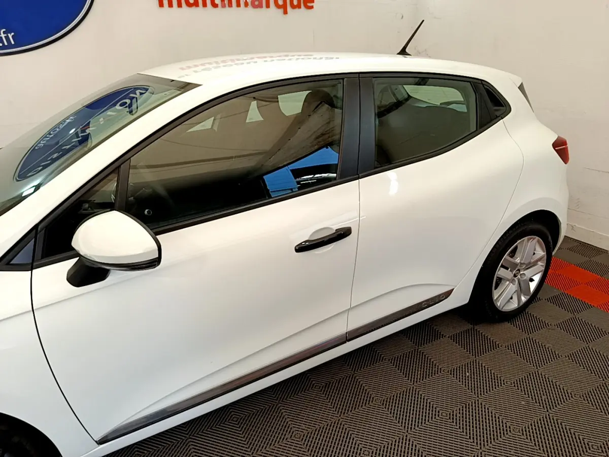 Profil côté gauche d'une Renault Clio Business blanche, mettant en valeur la ligne fluide et les jantes alliage.