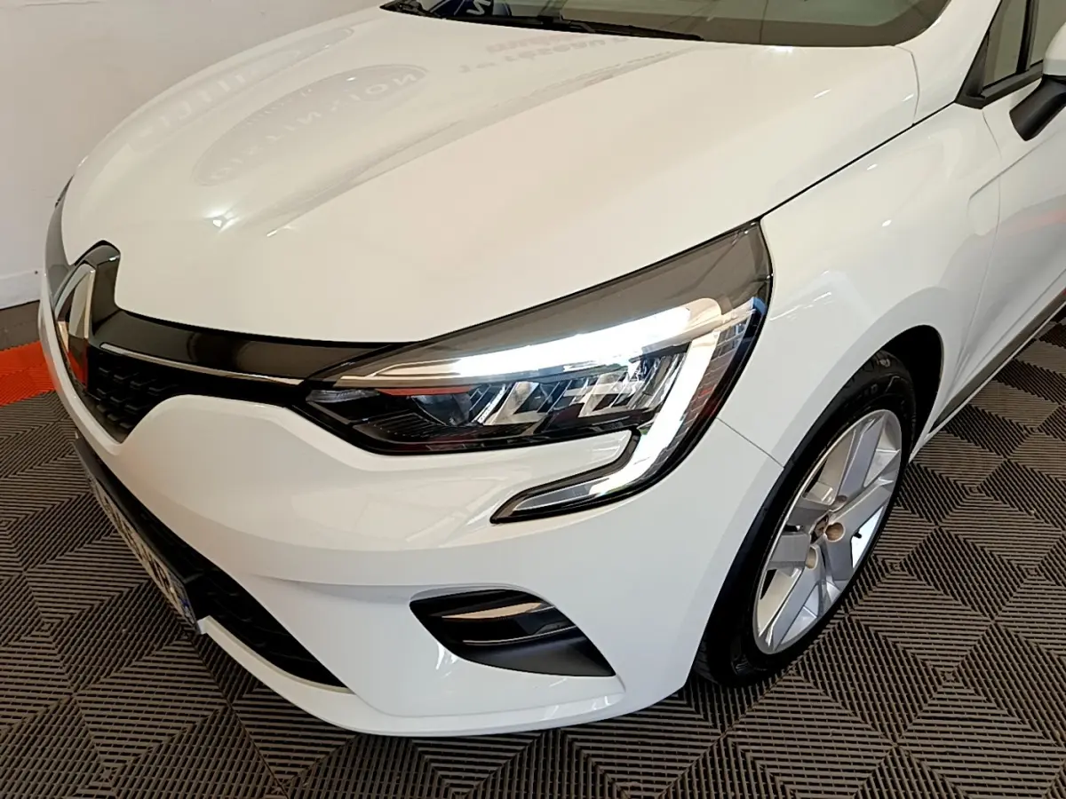 Vue 3/4 avant droit d'une Renault Clio Business blanche mettant en valeur ses phares LED et jantes alliage.