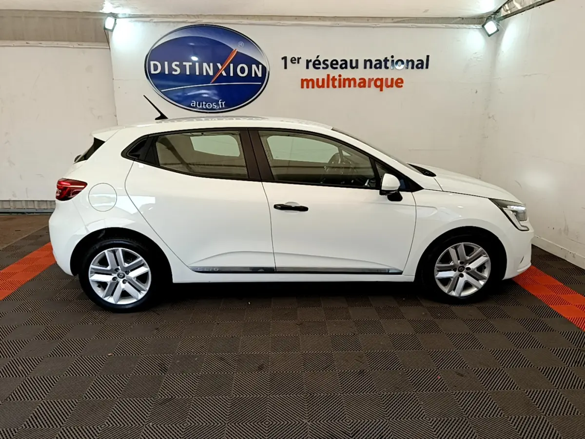 Profil droit d'une Renault Clio Business blanche 2021 dans un showroom avec logo Distinxion en arrière-plan.