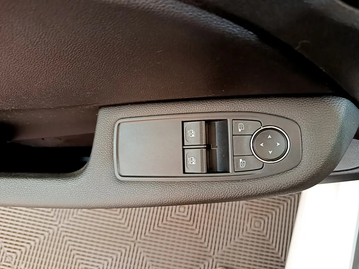 Commande des vitres et rétroviseurs électriques sur la portière côté gauche d'une Renault Clio Business blanche 2021.