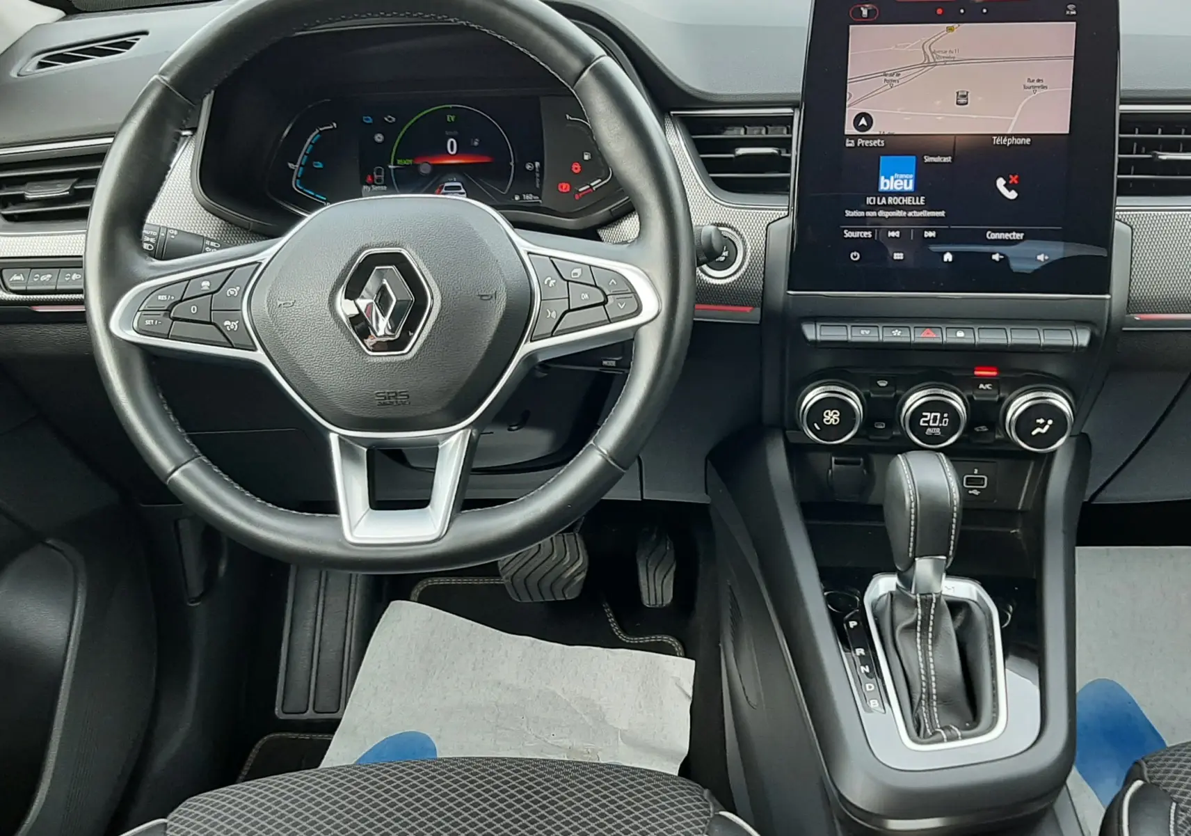 Vue intérieure centrée sur le volant et la console centrale avec écran tactile du Renault Arkana 1.6 E-TECH rouge Flame.