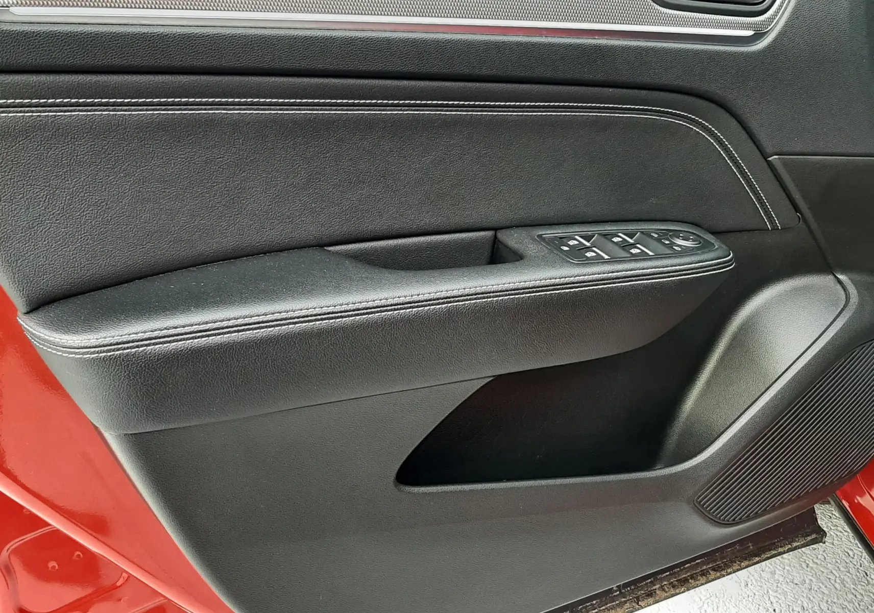 Vue rapprochée de la porte avant gauche rouge flame d’une Renault Arkana 1.6 E-TECH 145 Intens avec garniture intérieure noire.