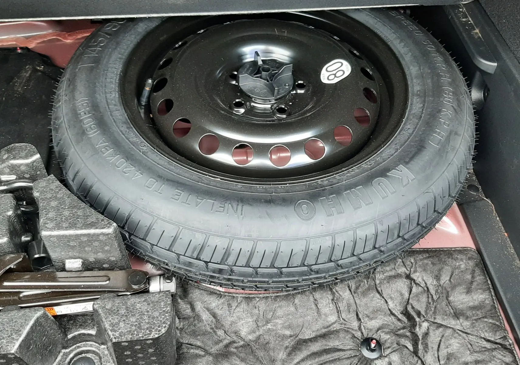 Pneu de secours noir dans le coffre d'une Renault Arkana Rouge Flame 2021, avec outils de changement visibles.