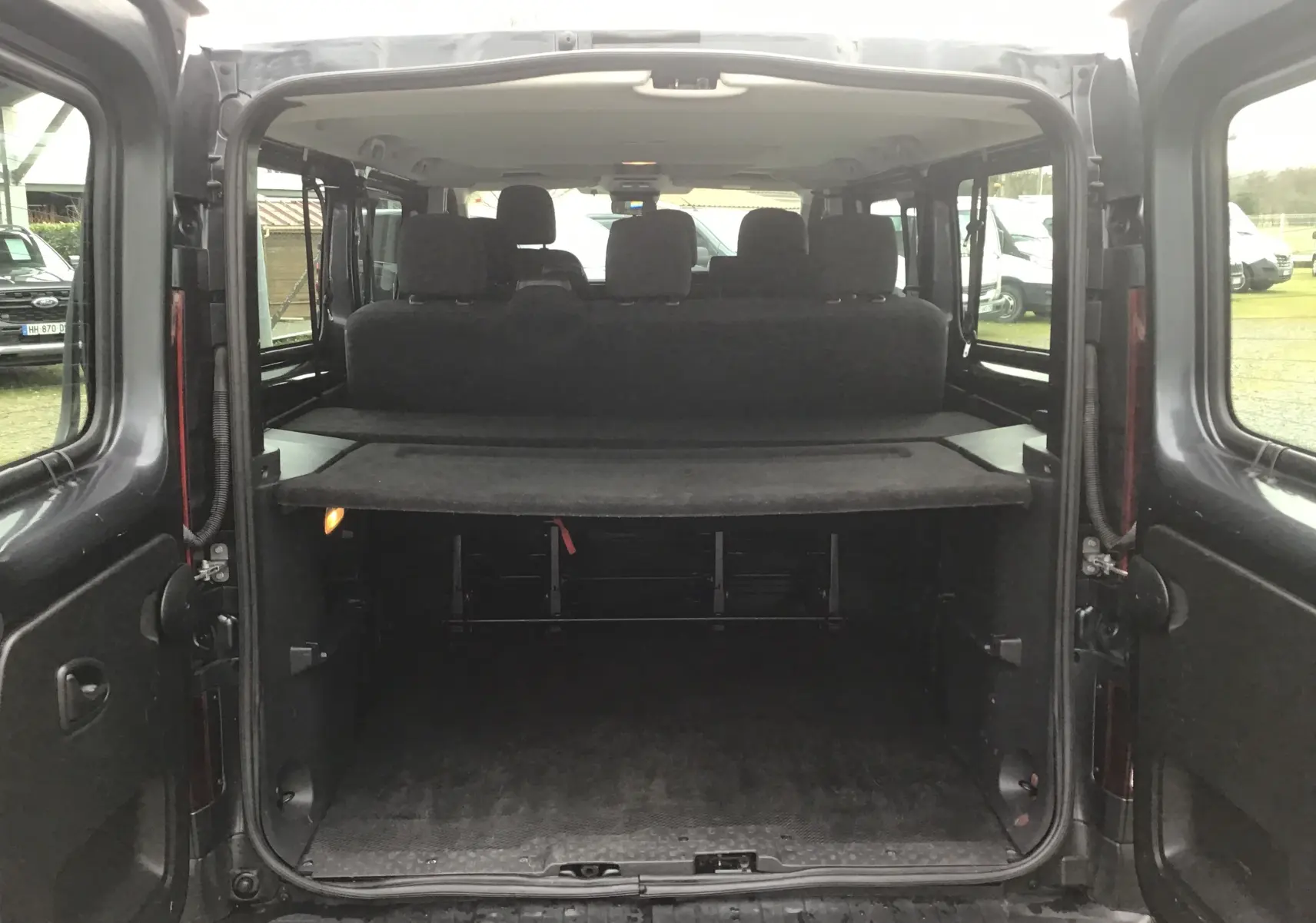 Vue arrière ouverte du Renault Trafic Combi gris comète, montrant l'espace de chargement et les sièges arrière.