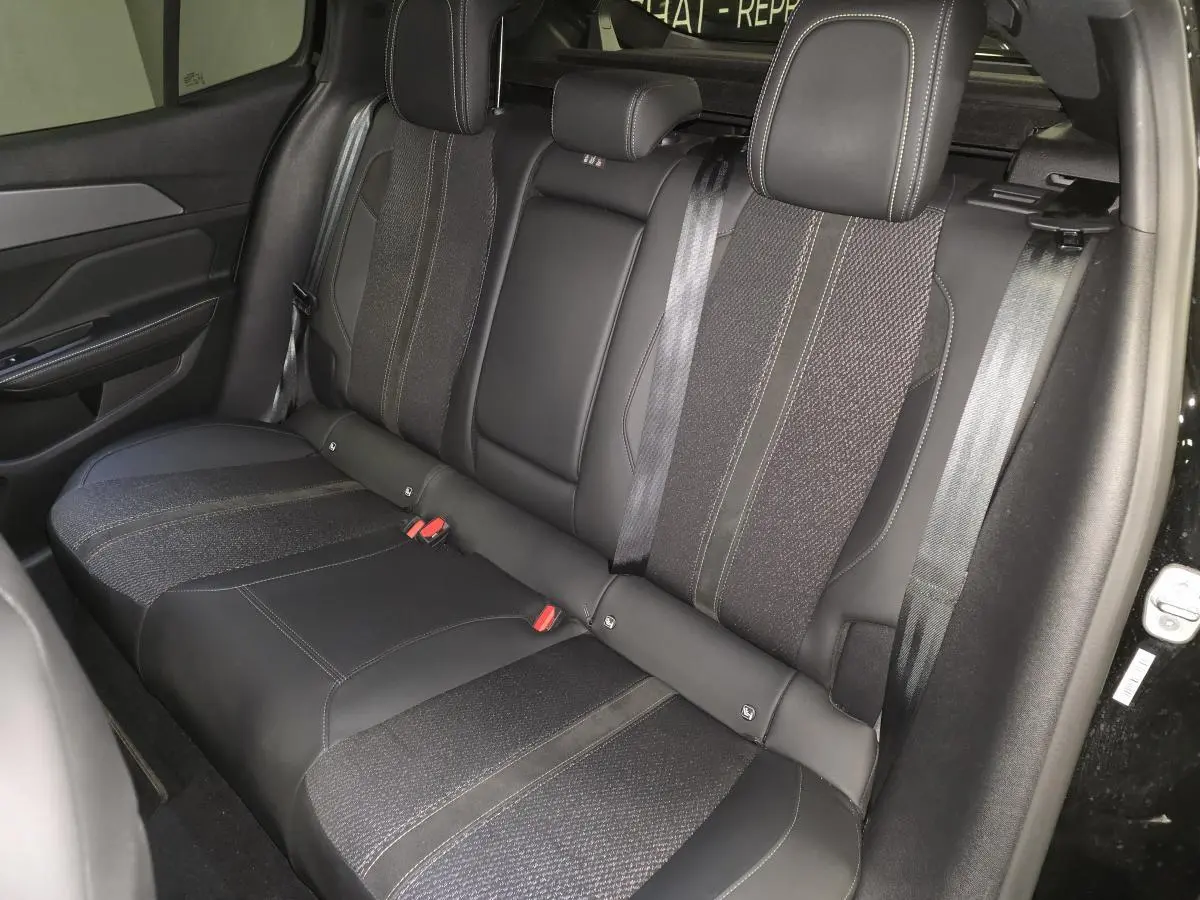 Vue intérieure côté droit de la banquette arrière noire en tissu et cuir du Peugeot 408 1.6 PHEV 2024 Berline GT