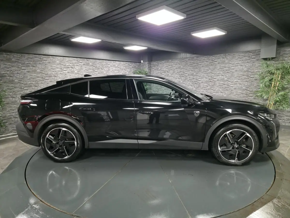 Vue latérale droite d'une Peugeot 408 noire brillante avec jantes alliage 19 pouces et badge lion sur l'aile avant.