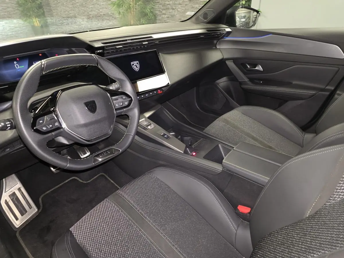 Intérieur avant de la Peugeot 408 noir, vue côté conducteur avec volant cuir perforé et écran tactile central.