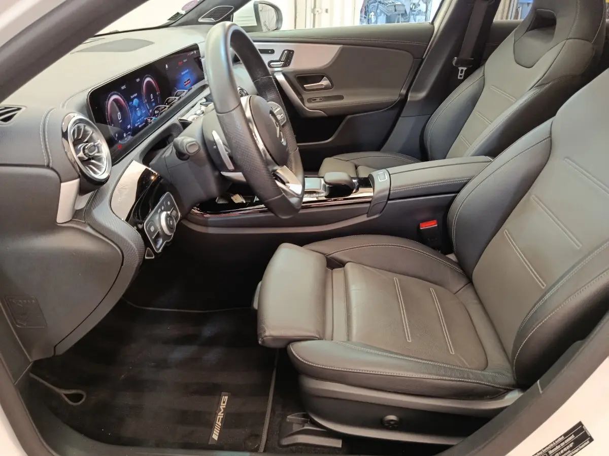 Vue intérieure côté conducteur de la Mercedes Classe A 250 e AMG Line 2021 avec sièges cuir noirs et tableau de bord numérique.