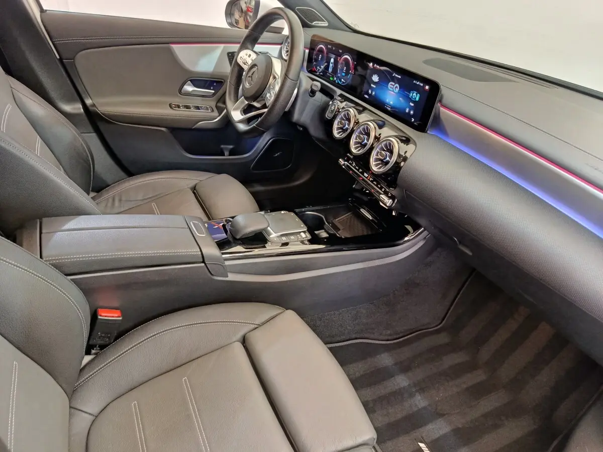 Vue intérieure côté conducteur de la Mercedes Classe A 250 e AMG Line 2021, avec tableau de bord numérique et éclairage d’ambiance coloré.