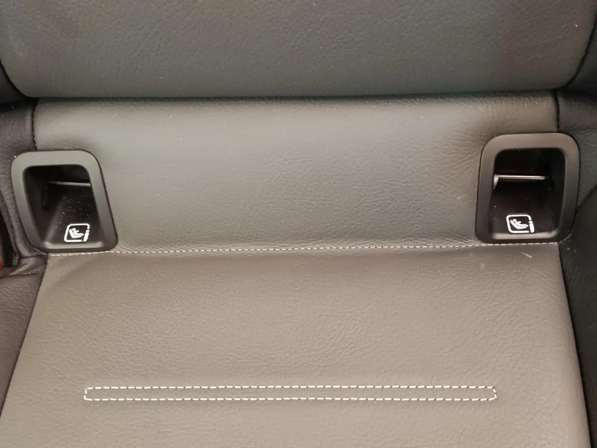 Gros plan sur les ancrages ISOFIX noirs intégrés dans la banquette arrière en cuir gris foncé d'une Mercedes Classe A blanche.